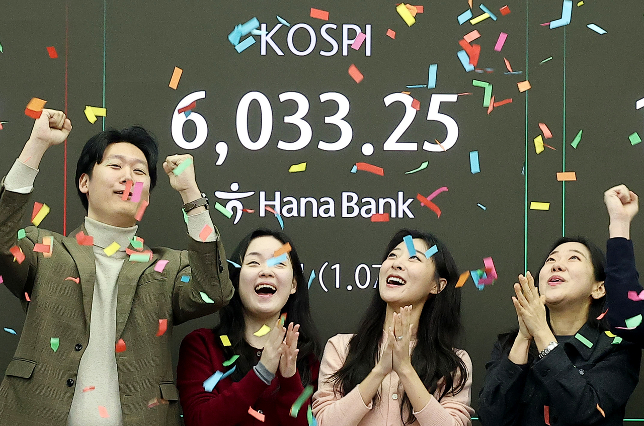 Traders cheer the benchmark Kospi surpasing the 6,000-point mark for the first time in early trading at the dealing room of Hana Bank in Seoul, Wednesday, (Yonhap)