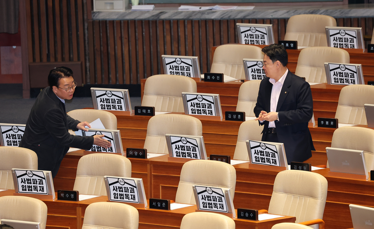 Rep. Kwak Kyu-taek of the main opposition People Power Part (left) places poster that reads "desctruction of law, legislative dictatorship" on People Power Party lawmakers' monitors at the National Assembly on Wednesday. (Yonhap)