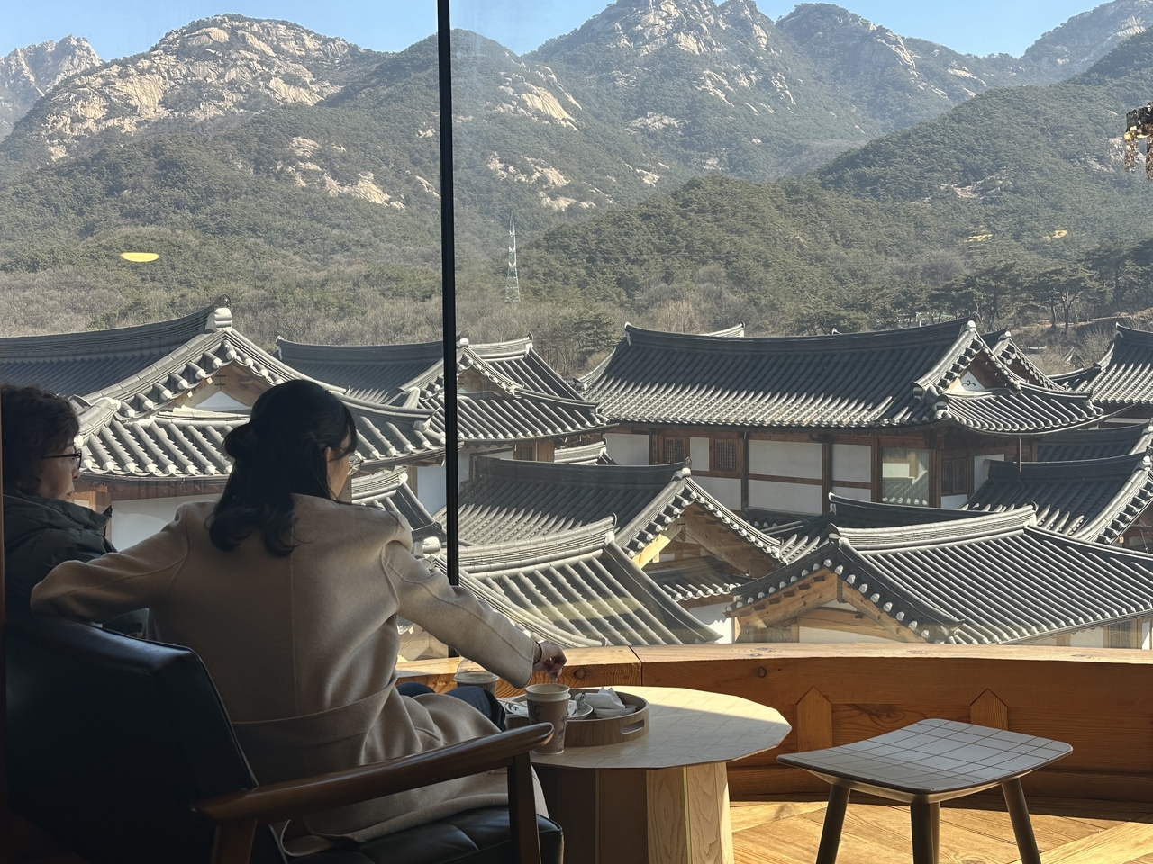 Visitors enjoy drinks and snacks by the window at Irin Iljan in Eunpyeong, northern Seoul. (Lee Jung-joo/The Korea Herald)