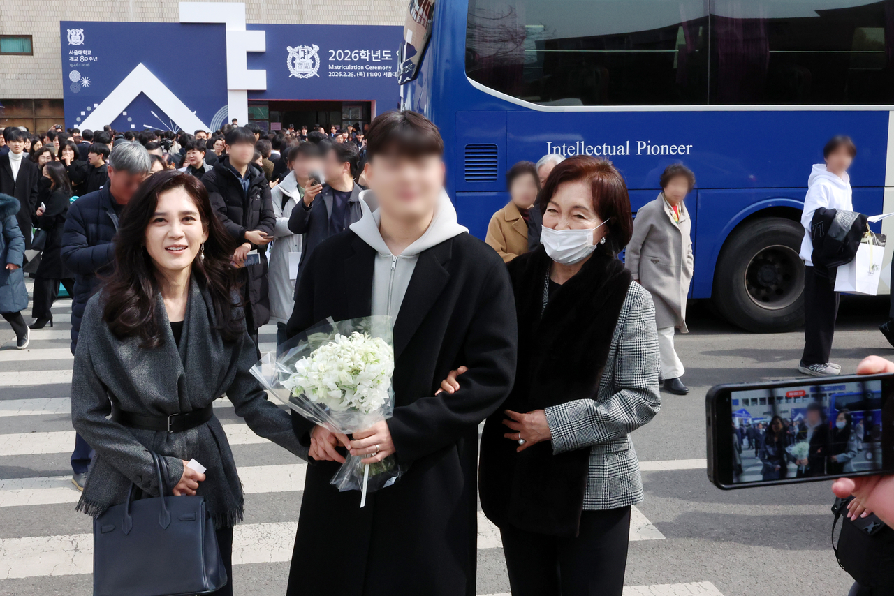 Hotel Shilla President Lee Boo-jin (left) and Leeum Museum of Art Honorary Director Hong Ra-hee (right) congratulate Lee’s son Lim Dong-hyun during Seoul National University’s entrance ceremony in Seoul on Thursday. (Newsis)