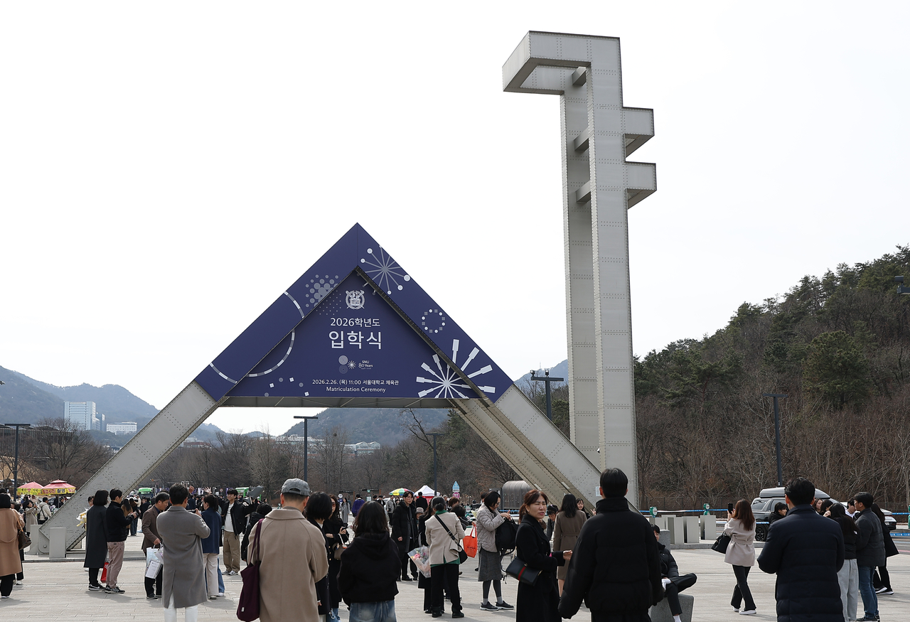 Students and their parents pose for photos at the main gate of Seoul National University in Seoul on Thursday. (Yonhap)