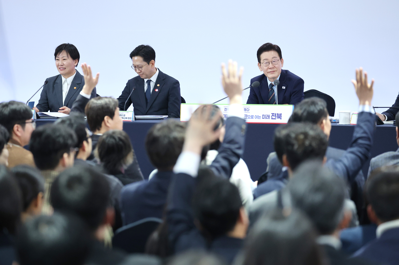Participants raise their hands to request to speak during a  town hall meeting at Jeonbuk National University in Jeonju, North Jeolla Province, on Friday, attended by President Lee Jae Myung. (Pool Photo  via Yonhap)