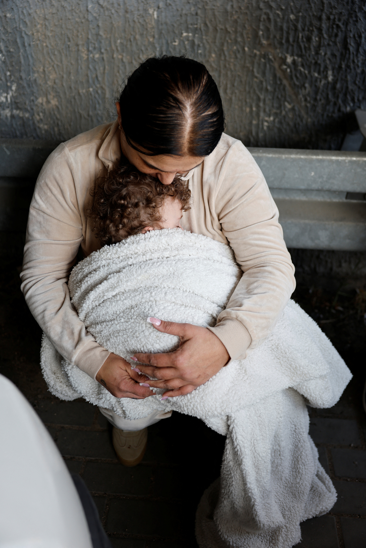 A woman holds a child as they take shelter under the bridge of a highway after Israel's military announced they identified missiles launched from Iran towards Israel and sirens are sounded, near Latrun, Israel, \Saturday. (Reuters-Yonhap)