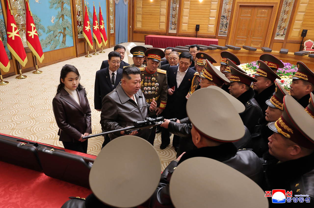 North Korea's leader Kim Jong-un (C) presents a new type of sniper rifle to major party and military officials as "special gifts" on Saturday in this photo carried by North Korea's official Korean Central News Agency the previous day. (Yonhap)