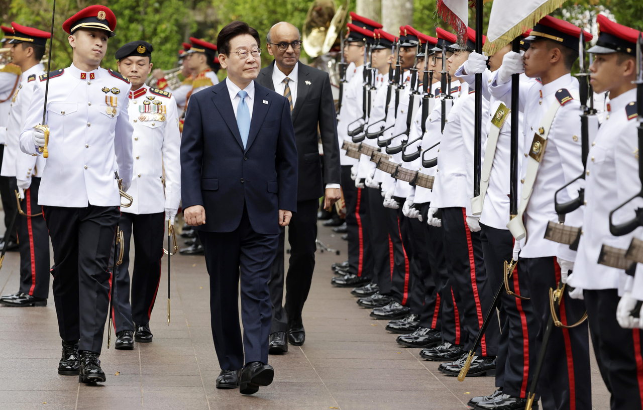 President Lee Jae Myung (center) reviews an honor guard with Singaporean President Tharman Shanmugaratnam during an official welcome ceremony for his state visit at Singapore’s Ministry of Foreign Affairs on Monday. (Yonhap)