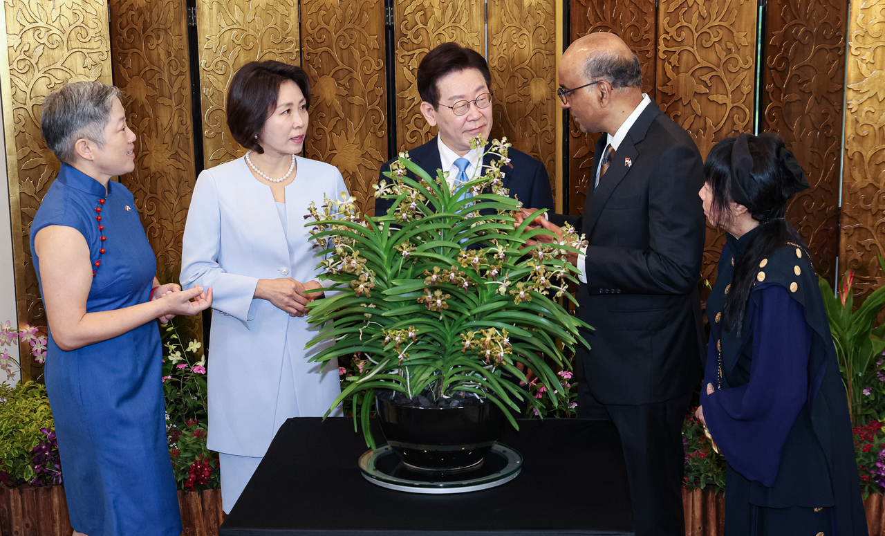 President Lee Jae Myung (center) and first lady Kim Hye-kyung (second from left) attend an orchid-naming ceremony with Singaporean President Tharman Shanmugaratnam (second from right) and his wife, Jane Ittogi Shanmugaratnam (left) at Singapore’s Ministry of Foreign Affairs on Monday.