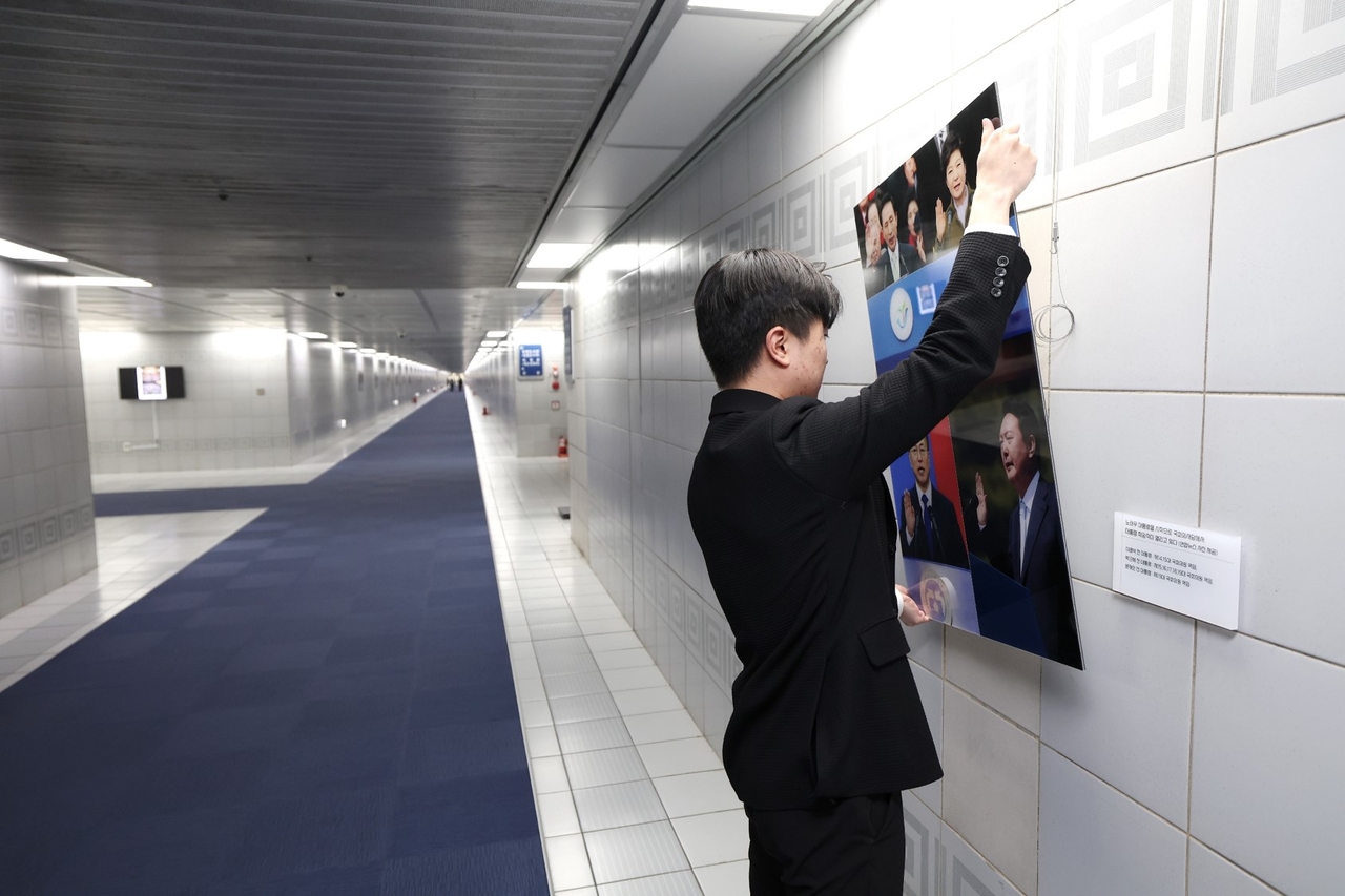 A National Assembly staff member is seen taking down a collage of former presidents, including Yoon Suk Yeol, Tuesday. (Courtesy of Rep. Woo Won-shik's office)