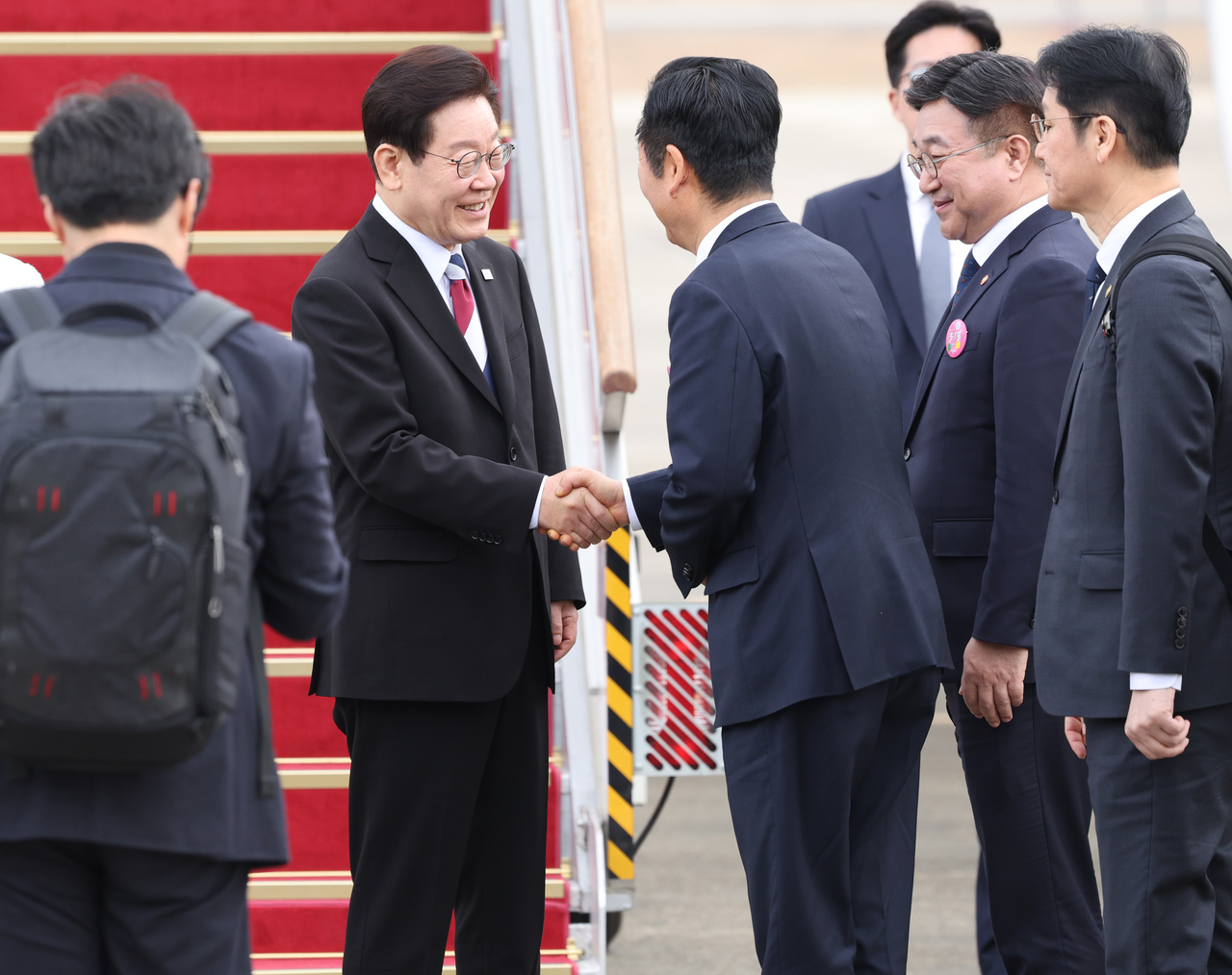 President Lee Jae Myung (second from left) and Democratic Party chair Rep. Jung Chung-rae (third from left) shake hands before Lee departed for Singapore at the Seoul Air Base in Seongnam, Gyeonggi Province, Sunday. This handshake scene was not included in the state-run KTV's YouTube clip that filmed the moment Lee departed South Korea for Singapore on Sunday. (Yonhap)