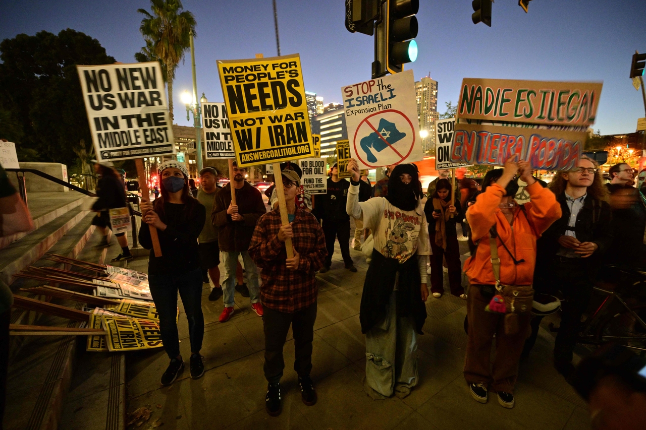 Demonstrators hold placards as they rally against military action in Iran outside of City Hall in Los Angeles, Monday. (AFP-Yonhap)