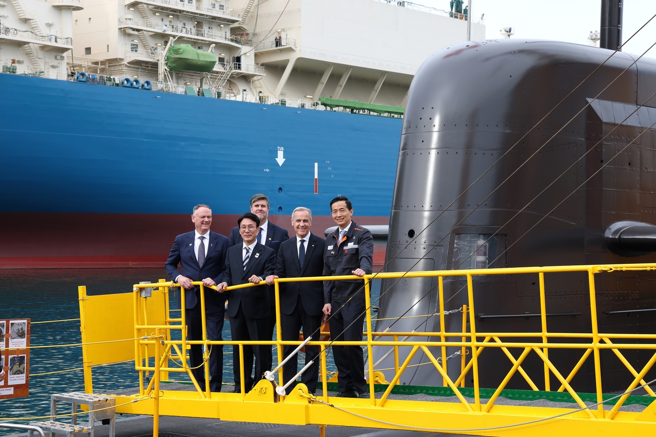 Canadian Prime Minister Mark Carney (front, third from left), South Korean Prime Minister Kim Min-seok (front, second from left) and Kim Dong-kwan (front right), vice chair of Hanwha Group, pose aboard the Jang Yeong-sil, a submarine built by Hanwha Ocean, in Geoje, South Gyeongsang Province, Oct. 30, 2025. (Hanwha Ocean)