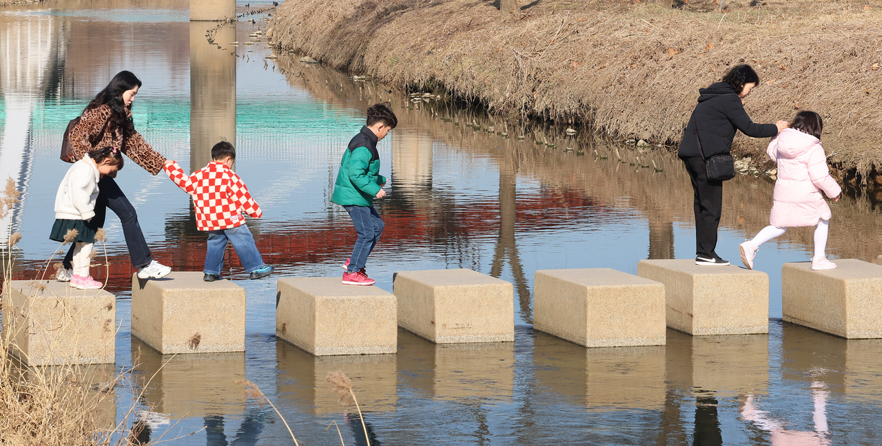 Families take a stroll at a stream in Incheon on Feb. 25. (Yonhap)