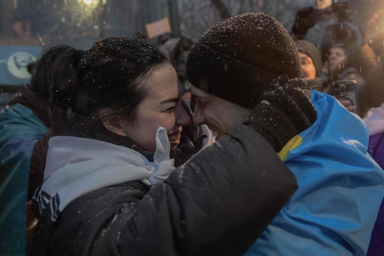 Olha Kurtmallaieva (left) hugs her husband Ruslan, 32, draped in a Ukrainian national flag, a released prisoner of war who was captured during the defense of Mariupol in 2022, upon his arrival after a prisoner exchange in the Chernihiv region, at an undiclosed location on February 5, 2026. (AFP)