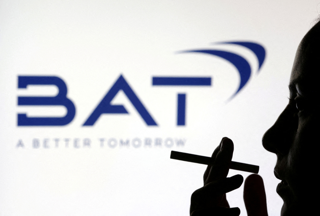 A woman poses with a cigarette in front of British American Tobacco logo in this illustration taken July 26, 2022. (Reuters-Yonhap)