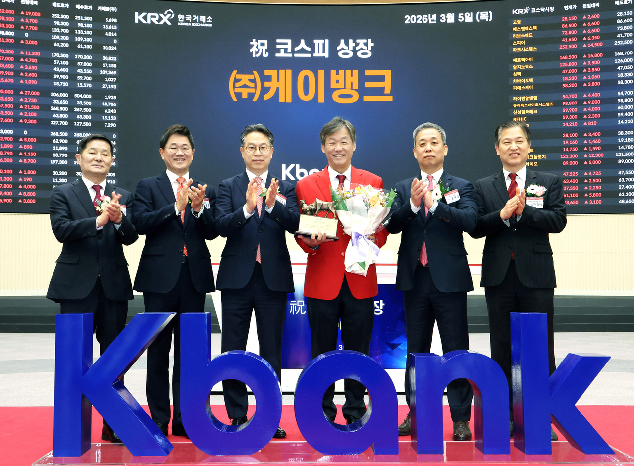 K bank CEO Choi Woo-hyung (in red) poses for photographs at the listing ceremony at the Korea Exchange in Seoul on Thursday. (Korea Exchange)