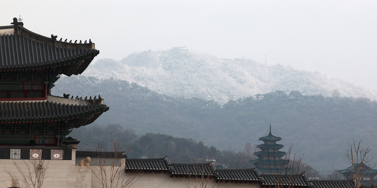 Snow covers parts of Bugaksan in Seoul, as sleet falls Friday. (Yonhap)
