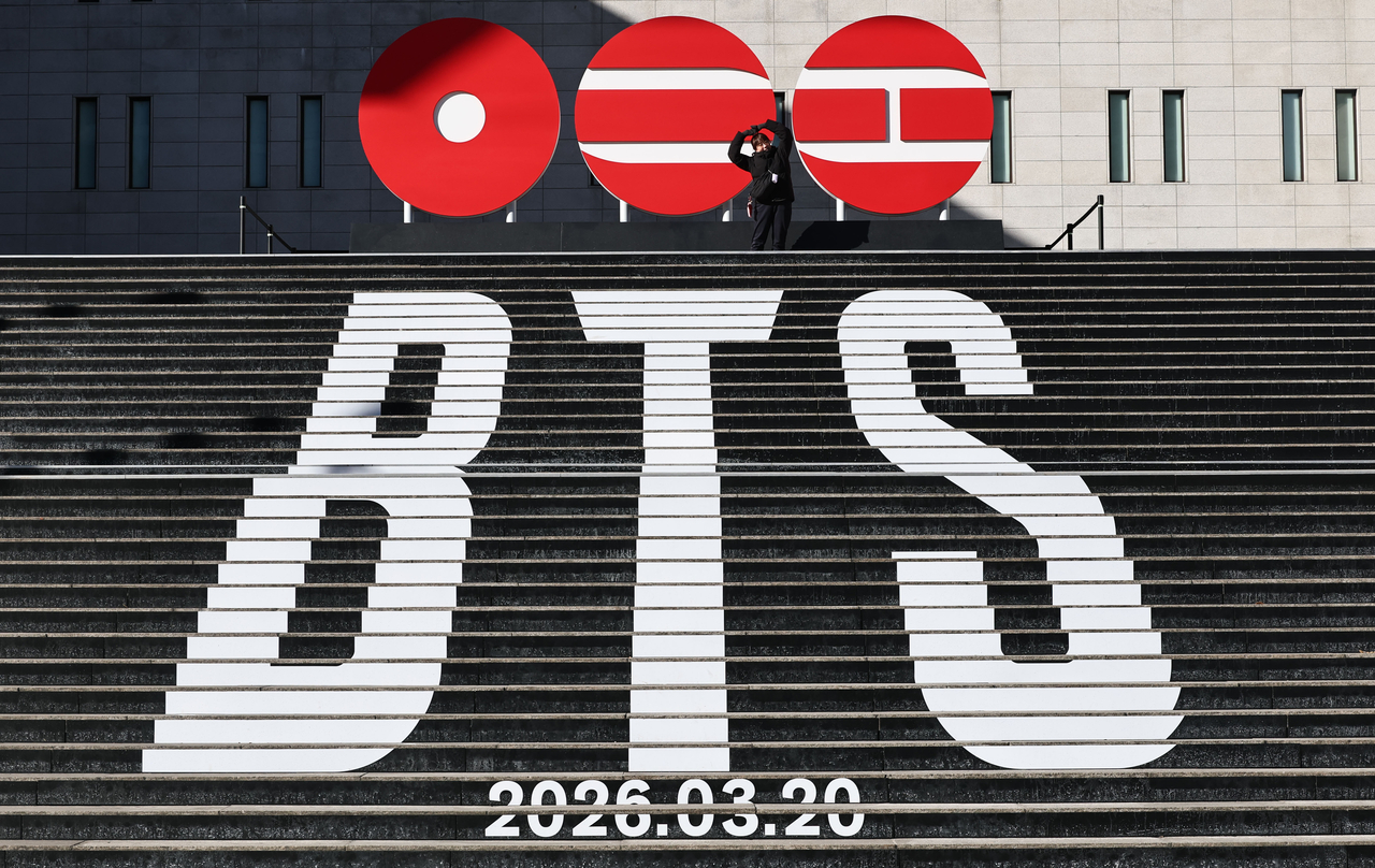 A fan poses on the stairs of the Sejong Center for the Performing Arts in central Seoul on Jan. 22, where a sculptural installation of BTS’ new album logo is on display. (Yonhap)