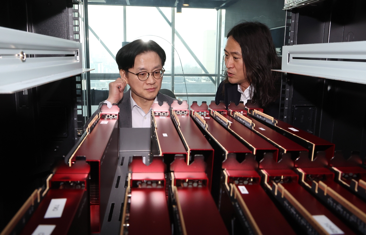 Industry Minister Kim Jung-kwan (left) examines FuriosaAI’s AI semiconductor servers as CEO June Paik explains the equipment at the company’s Seoul headquarters in Gangnam on Feb. 11.  (Yonhap)