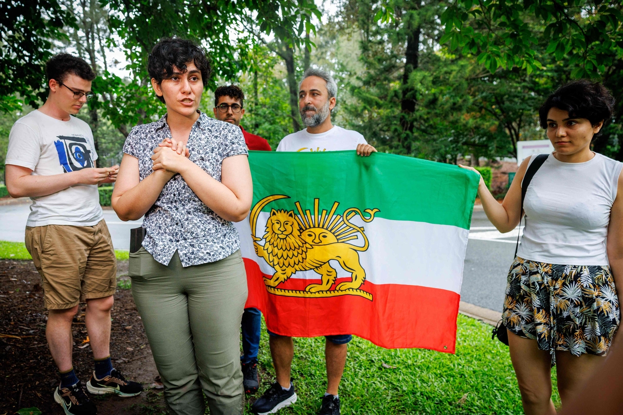 Members of the Iranian community in Australia stand with a pre-revolution Iranian flag in a show of support outside the Royal Pines Resort, where members of the Iranian women's soccer team are staying, in Gold Coast, Australia, Monday.   (AFP-Yonhap)