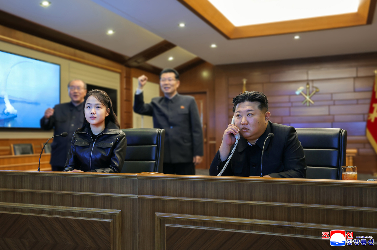 North's leader Kim Jong-un (right) and his daughter Ju-ae oversee a test-firing of strategic cruise missiles from the destroyer Choe Hyon via video on Tuesday. (KCNA via Yonhap)