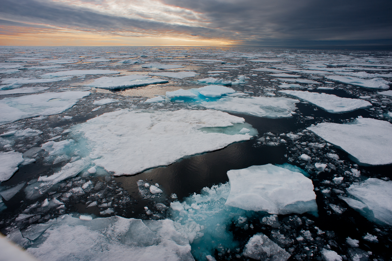 Northern Arctic ice floes are seen breaking up and melting leading into an atmospheric moody horizon with sunset.   123rf