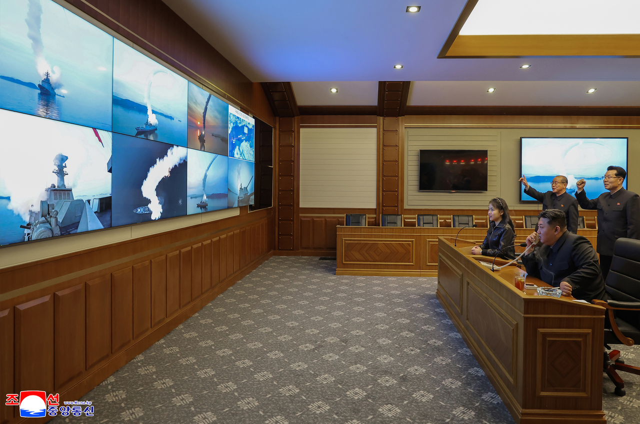 North Korean leader Kim Jong-un (right), alongside his daughter Ju-ae, oversees a test-firing of strategic cruise missiles from the Choe Hyon destroyer via video in Pyongyang on Tuesday, in this photo released by North Korea's official Korean Central News Agency the next day. (Yonhap)