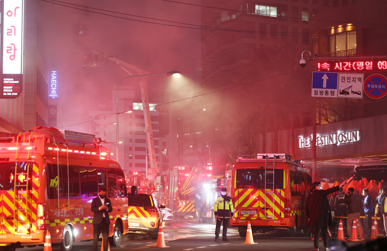 Fire trucks and emergency vehicles are parked as firefighters work to extinguish a blaze at a guest house on the third floor of a seven‑story building in Sogong‑dong, Jung‑gu, Seoul  on Saturday. (Yonhap)