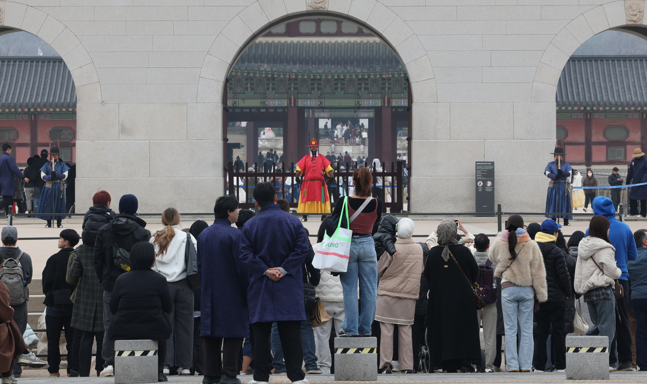 Tourists watch the changing of the royal guards ceremony at the Woldae platform in front of Gwanghwamun in Seoul on Sunday. (Yonhap)