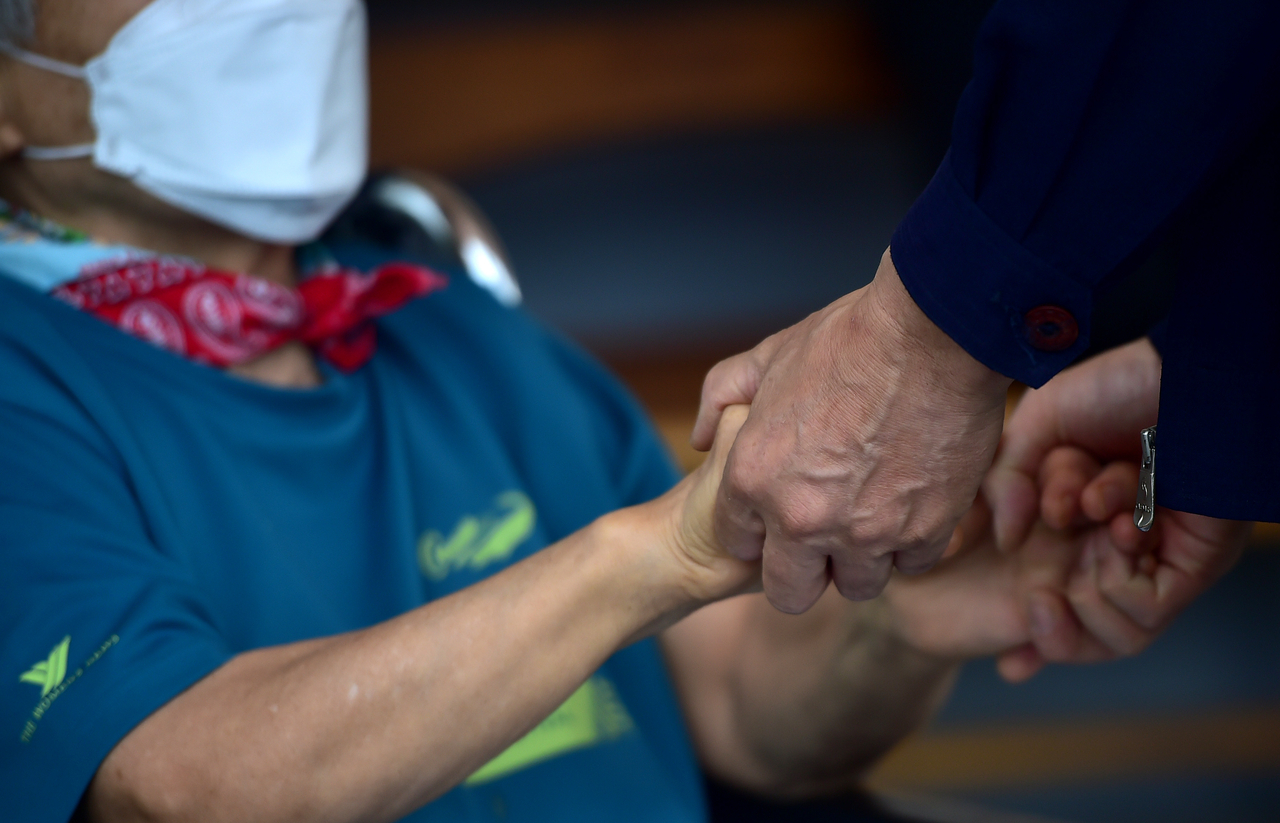 An elderly resident holds hands with her son during an in-person visit at a nursing home in Daegu. This image is not directly related to the story. (Newsis)