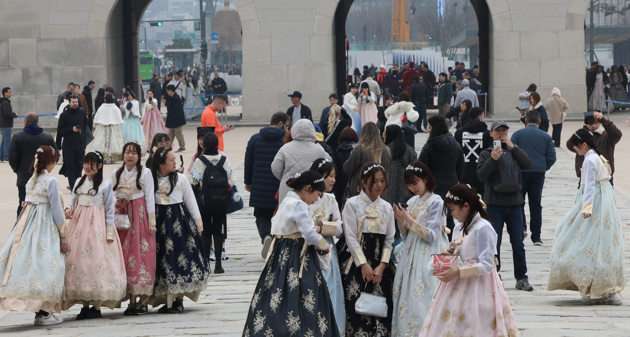 Tourists pose for photos during a visit to Gyeongbokgung in Seoul on Sunday. (Yonhap)