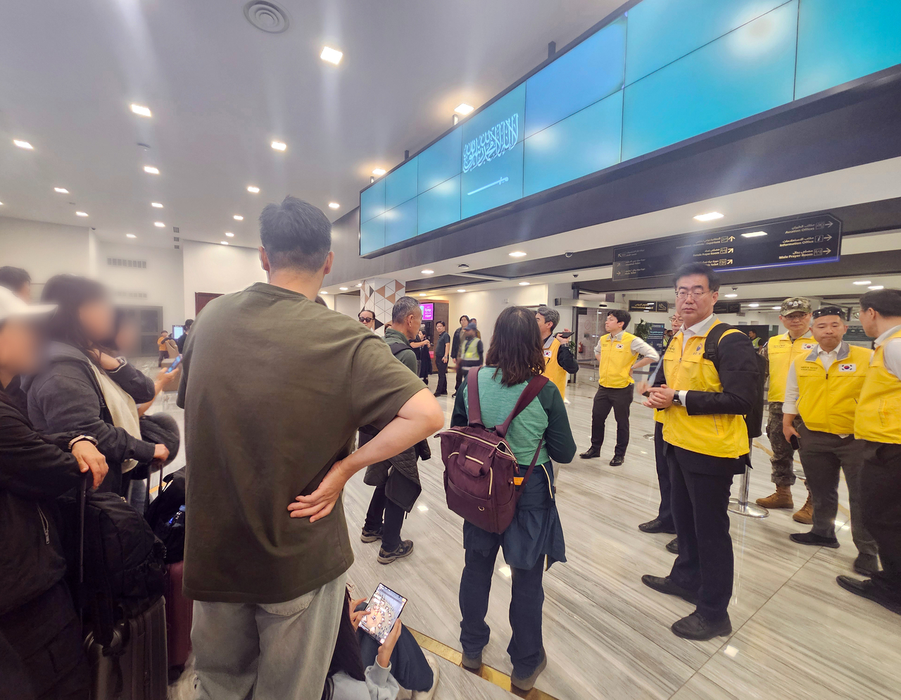 South Korean nationals and officials of a government rapid response team, wearing yellow vests, wait to board a military plane to return home from Saudi Arabia on Saturday in this photo provided by the Foreign Ministry. (Yonhap)