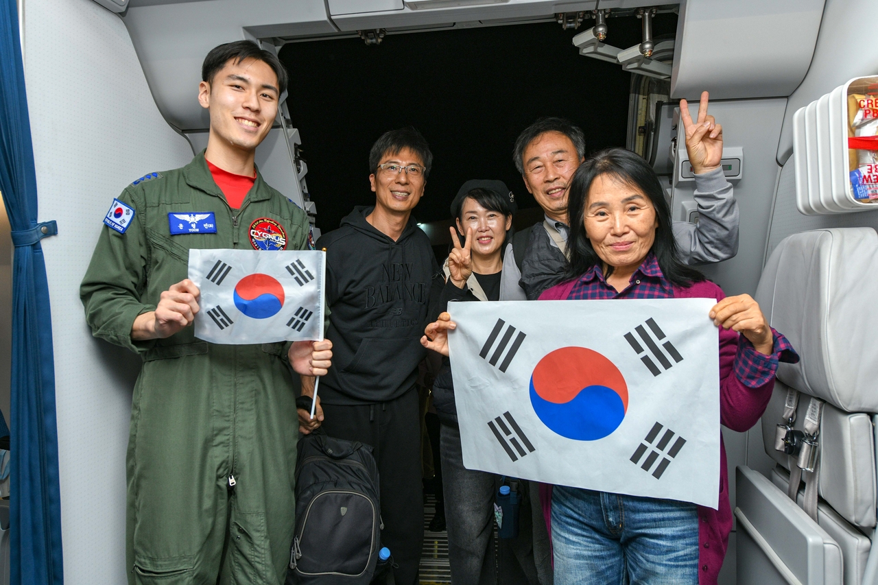 A South Korean family poses with an Air Force officer aboard a military plane bringing them and more than 200 others home from Saudi Arabia on Sunday, in an evacuation operation amid the Middle East conflict, in this photo provided by the Foreign Ministry. (Yonhap)