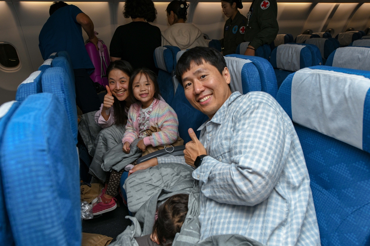 A family poses for photos aboard a military plane bringing them and more than 200 others home from Saudi Arabia on Sunday, in an evacuation operation amid the Middle East conflict, in this photo provided by the Foreign Ministry. (Yonhap)