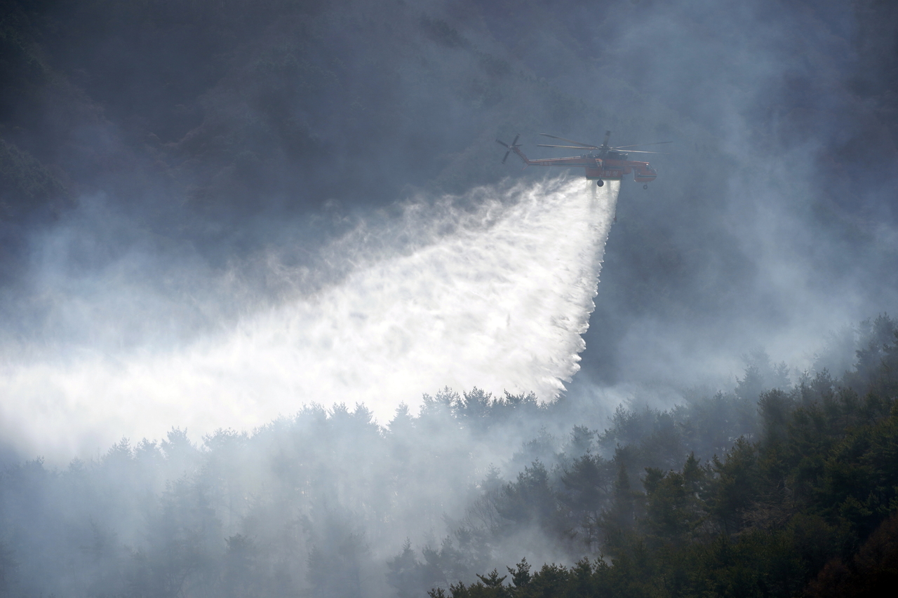A helicopter works to extinguish a wildfire in Macheon-myeon, Hamyang, South Gyeongsang Province, on Feb. 23, 2026. (Yonhap)