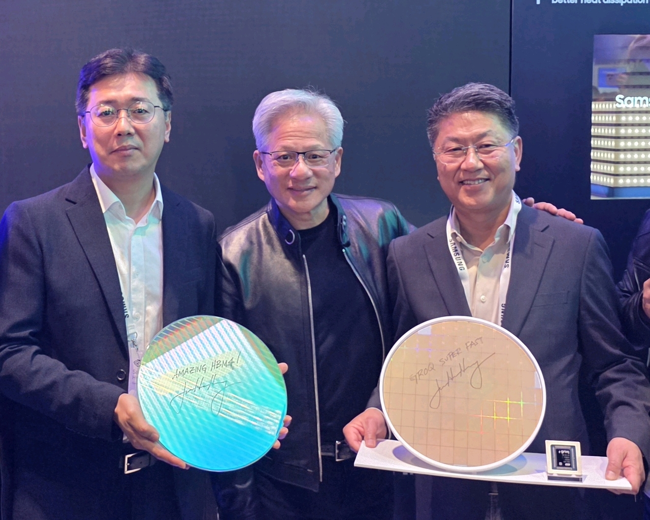 From left: Hwang Sang-joon, head of memory development at Samsung Electronics, Nvidia CEO Jensen Huang and Han Jin-man, head of foundry business at Samsung Electronics, pose for a photo holding a Samsung HBM4 core die wafer and Nvidia’s Groq 3 LPU 4-nanometer wafer at the Samsung booth during Nvidia GTC 2026 in San Jose, California, Monday. (Samsung Electronics)