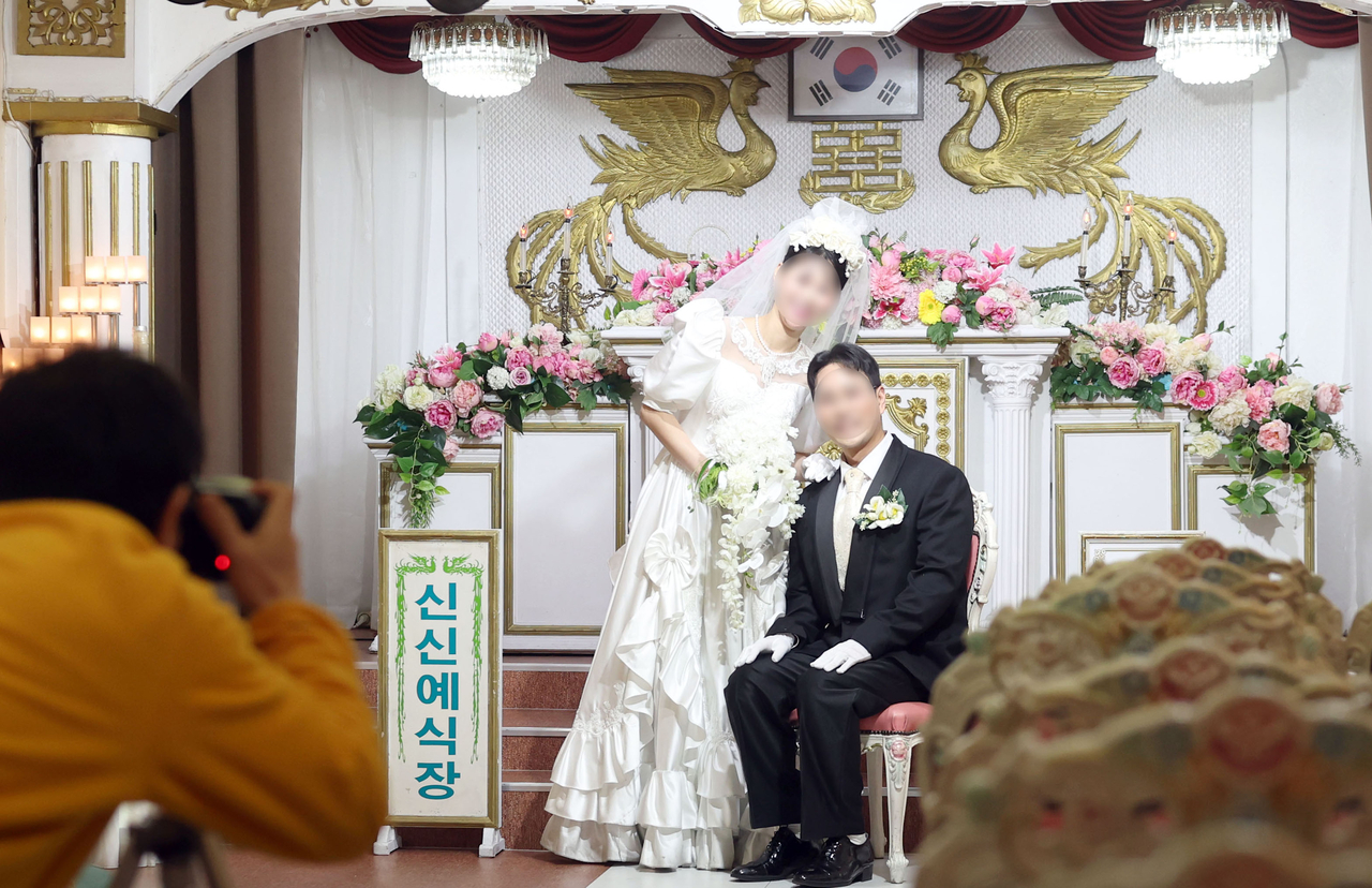 A newlywed couple takes a photograph at a wedding hall in Changwon, South Gyeongsang Province, March 14. (Yonhap)