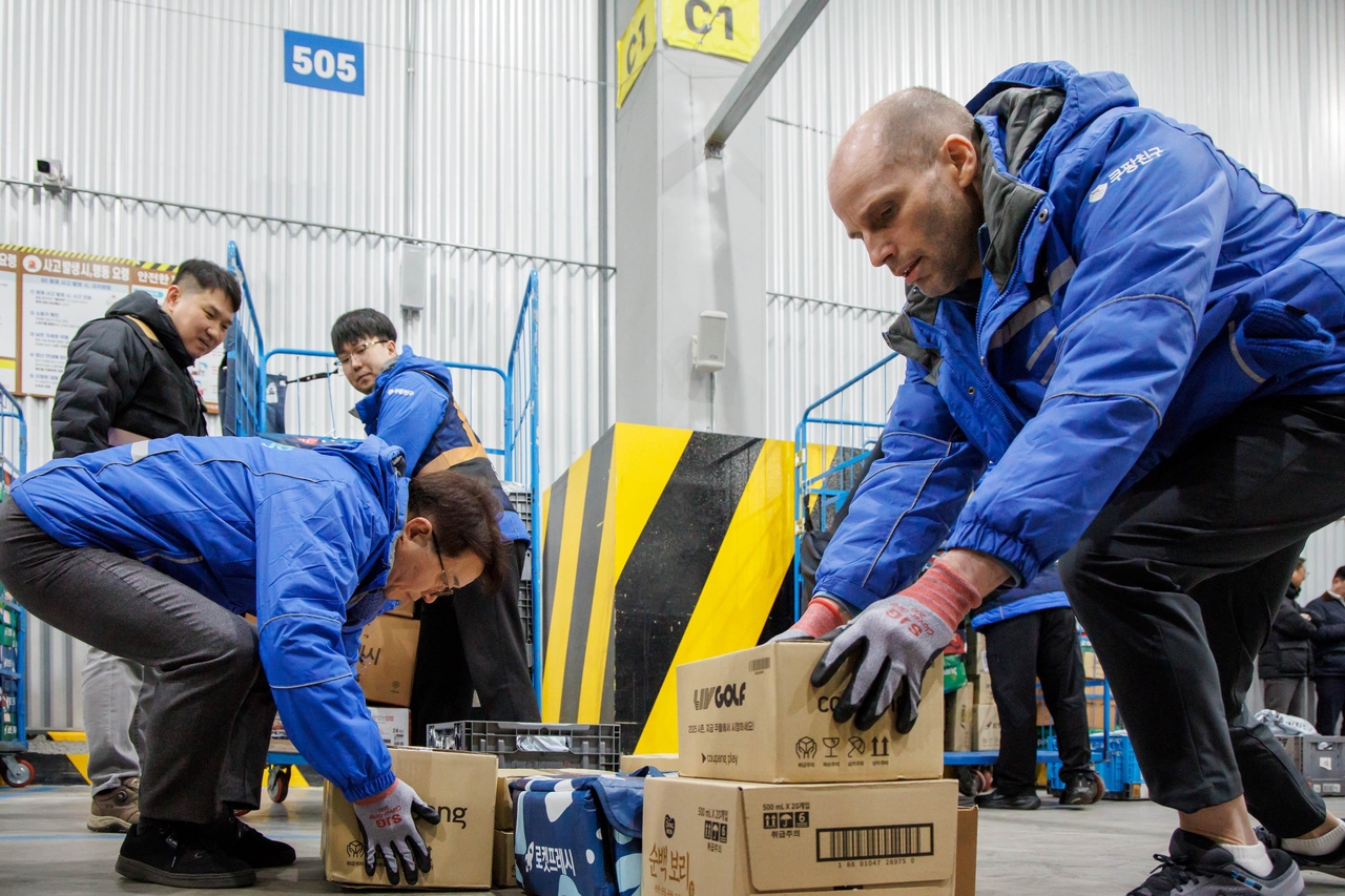 Coupang interim CEO Harold Rogers (right) picks up a delivery package at a Coupang logistics service center in Seongnam, Gyeonggi Province on Thursday. (Coupang)