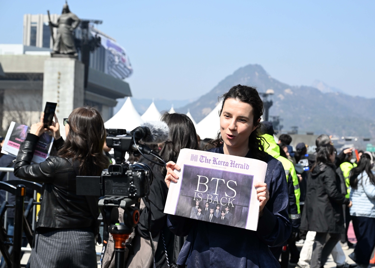 A foreign journalist holds up a special edition of The Korea Herald in front of a TV camera while reporting.  (The Korea Herald/ Lee Sang-sub)