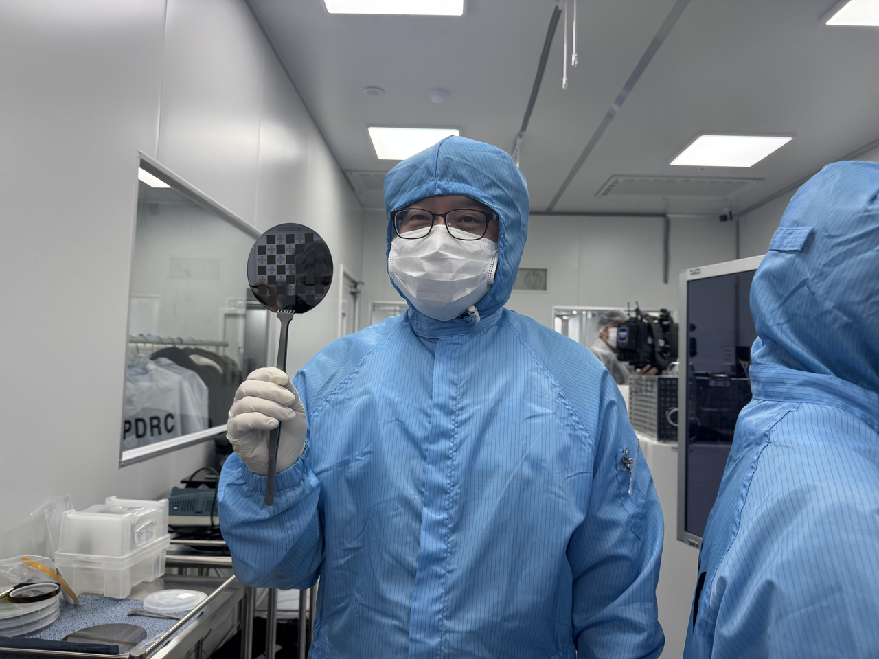 A semiconductor engineering professor holds up an etched semiconductor wafer on Wednesday at Myongji University's Yongin Campus in Gyeonggi Province. (Lee Seung-ku/The Korea Herald)