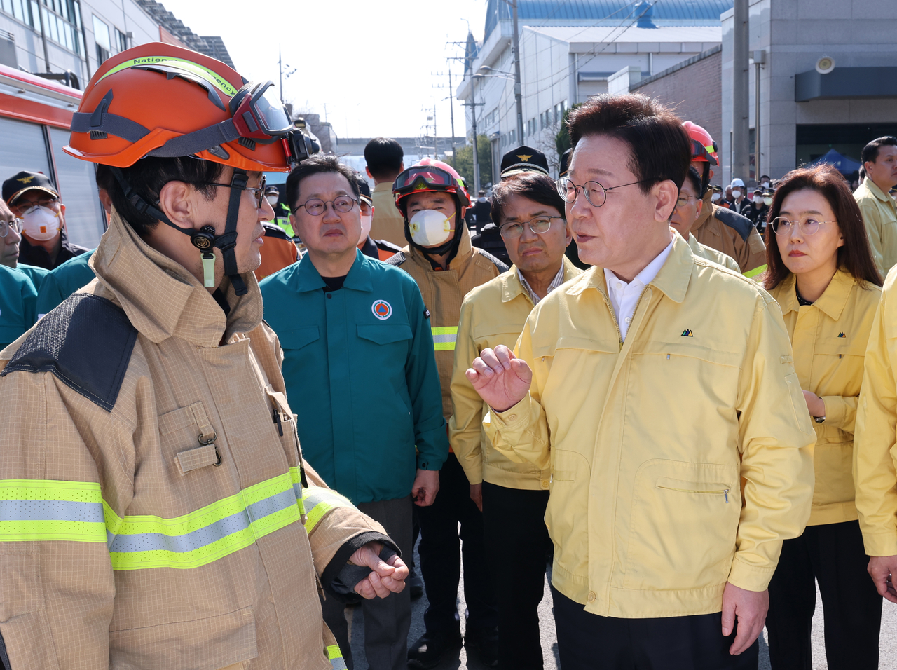 President Lee Jae Myung (right) is briefed on the fire at a car parts factory in the central city of Daejeon on Saturday, during his visit to the site a day after the blaze.  (Yonhap)