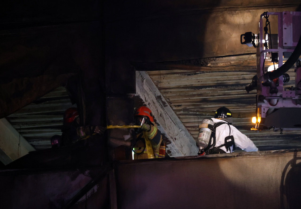 Firefighters conduct an overnight search for missing people at a car parts plant after a large fire engulfed the building in the central city of Daejeon, killing at least 10 people, in this photo taken on Saturday. (Yonhap)