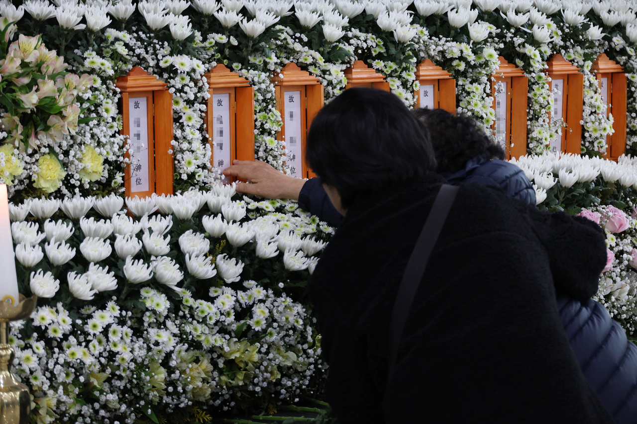 A bereaved family member touches her son’s name at the joint memorial altar for victims of the Daejeon factory fire set up at Daejeon City Hall on Sunday. (Yonhap)