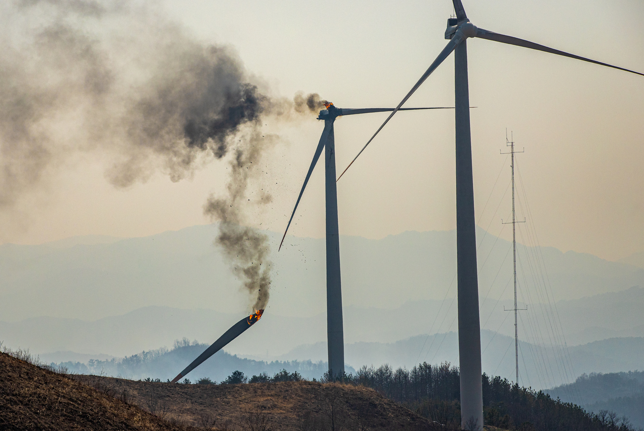A flaming wind turbine propeller breaks off and falls at a wind power complex in Yeongdeok, North Gyeongsang Province, on Monday. (Yonhap)