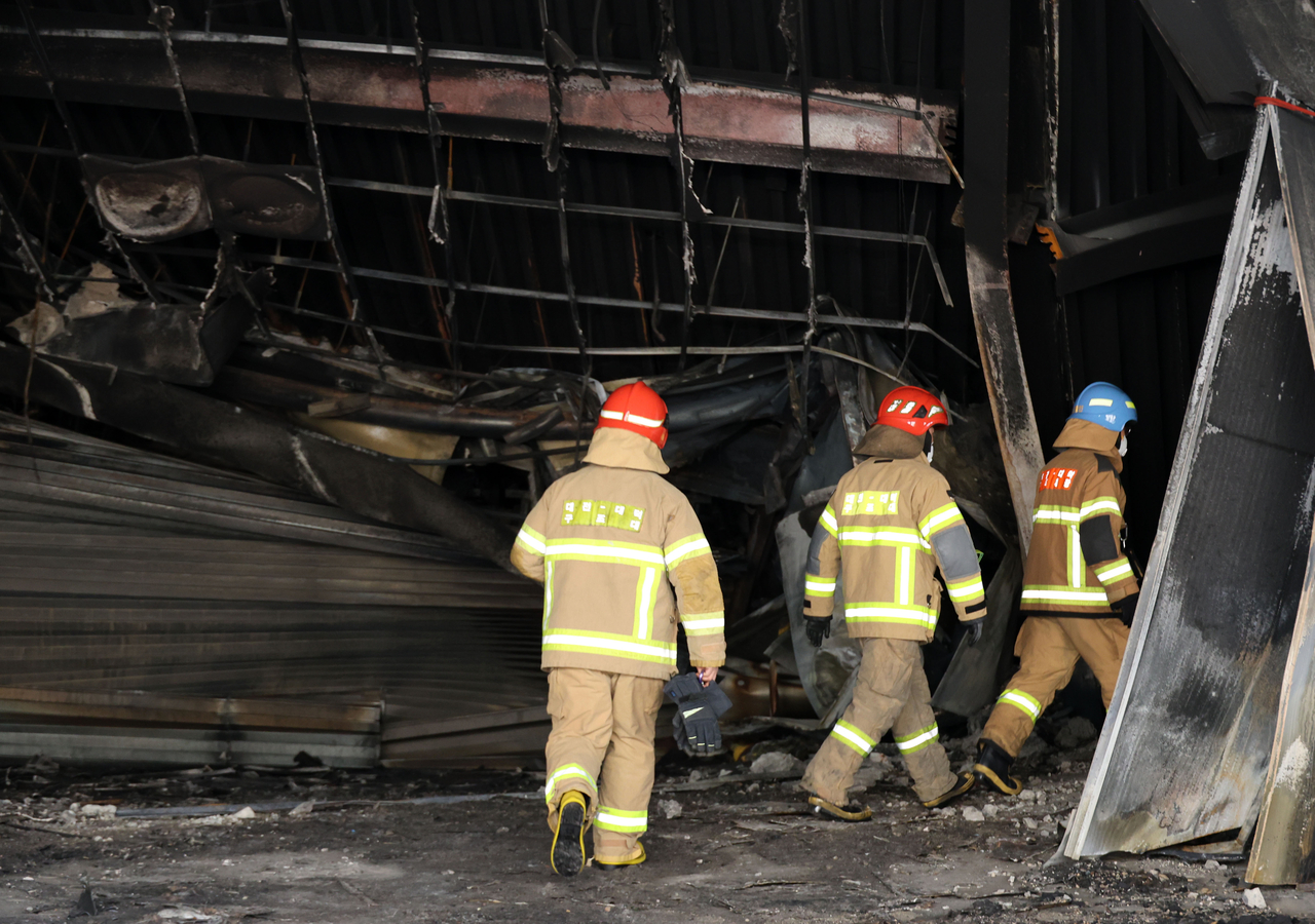 Firefighters on Monday investigate the site of Friday's deadly factory fire in Daejeon. (Yonhap)