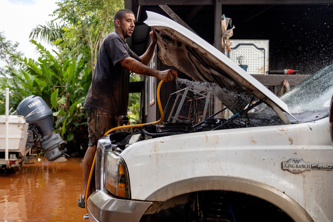 A person flushes mud from his lifted truck's engine bay the day after it was fully submerged in Haleiwa, Hawaii, Saturday. (AP-Yonhap)