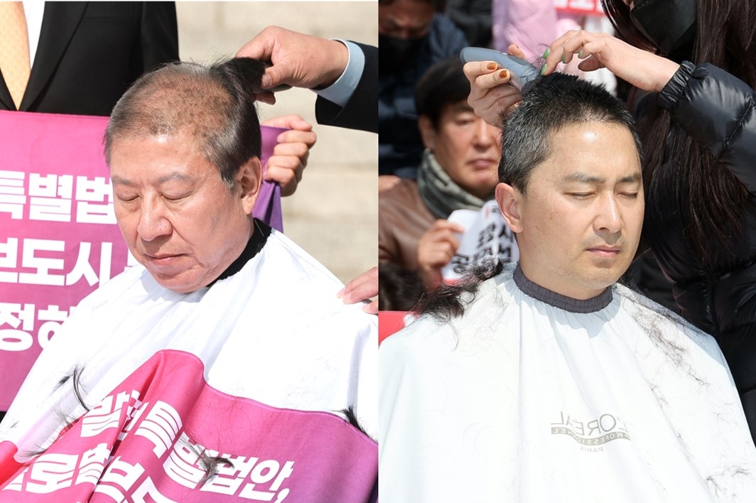 Busan Mayor Park Heong-joon (left) and Kim Byong-wook, a hopeful candidate for mayor of Pohang, have their heads shaved in front of the National Assembly's main building on Monday. (Yonhap)