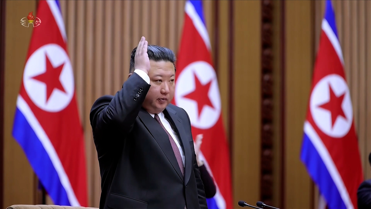 North Korean leader Kim Jong-un raises his hand in response to applause during a session of the 15th Supreme People’s Assembly in Pyongyang, Sunday. (Korean Central Television via Yonhap)
