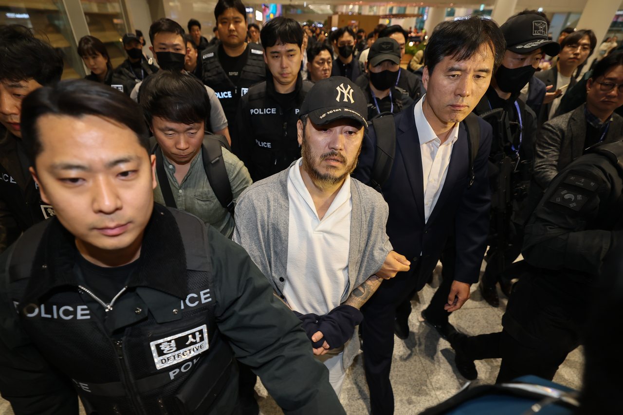 Park Wang-yeol (center), a convicted criminal accused of smuggling drugs into South Korea, is escorted by police officials at Incheon International Airport, west of Seoul, Wednesday. (Yonhap)