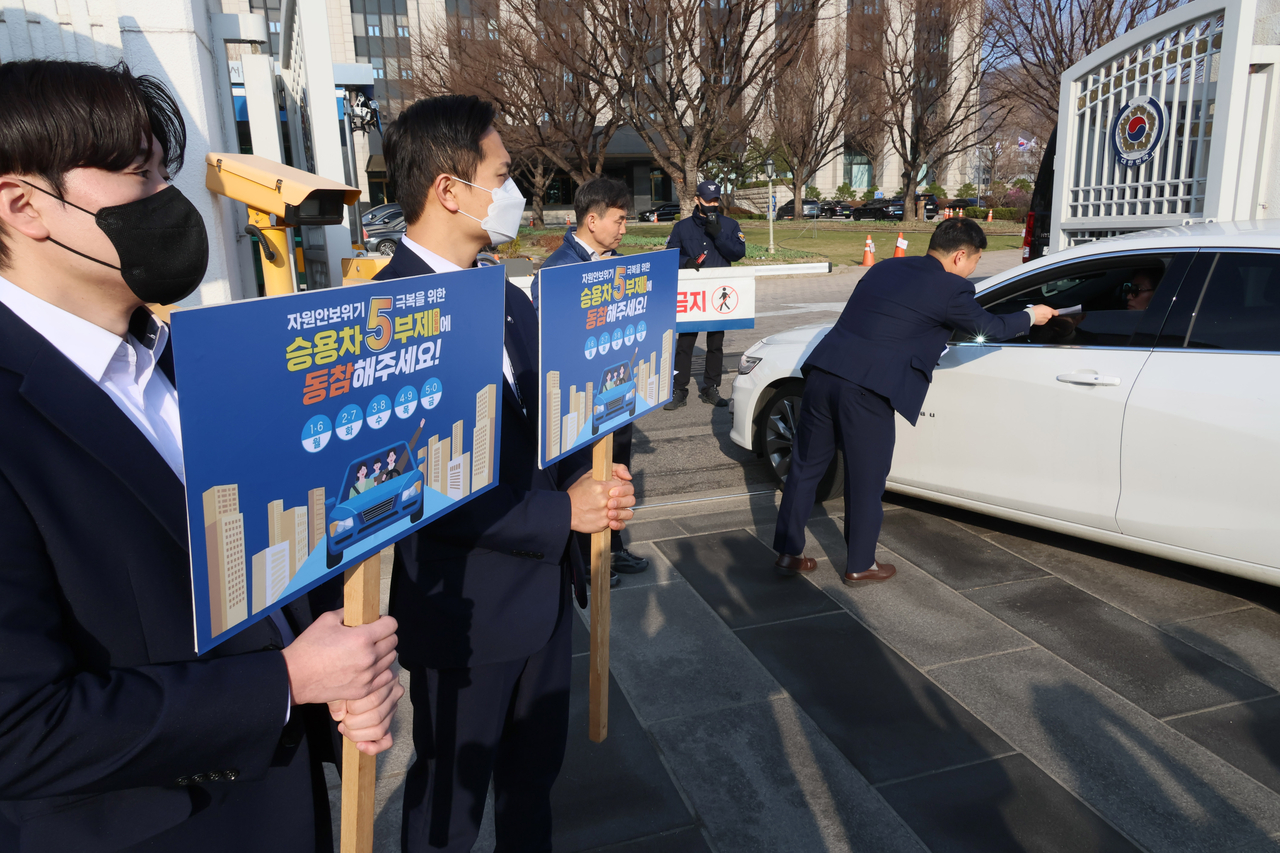 Officials hold signs Wednesday at the Government Complex Seoul, home to ministries including Foreign Affairs, to promote the five-day vehicle restriction campaign. (Yonhap)