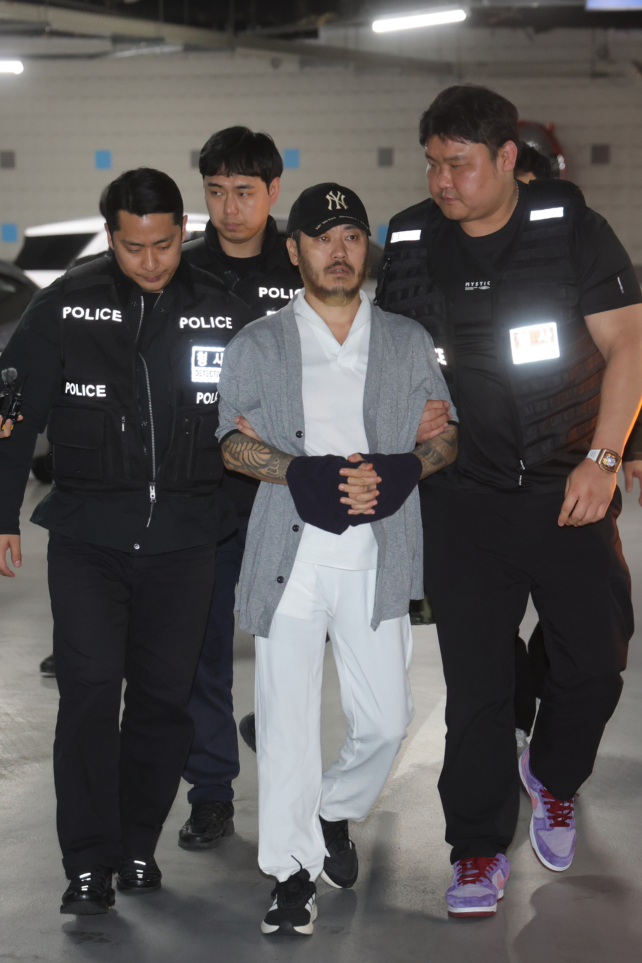 Park Wang-yeol is escorted by police officials as he arrives at Incheon International Airport on Wednesday. (Yonhap)