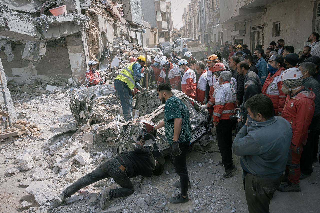 First responders inspect a destroyed car at the site of a residential building hit in an overnight strike during the US-Israeli military campaign in Tabriz, East Azerbaijan Province, northwestern Iran, Tuesday. (AP-Yonhap)